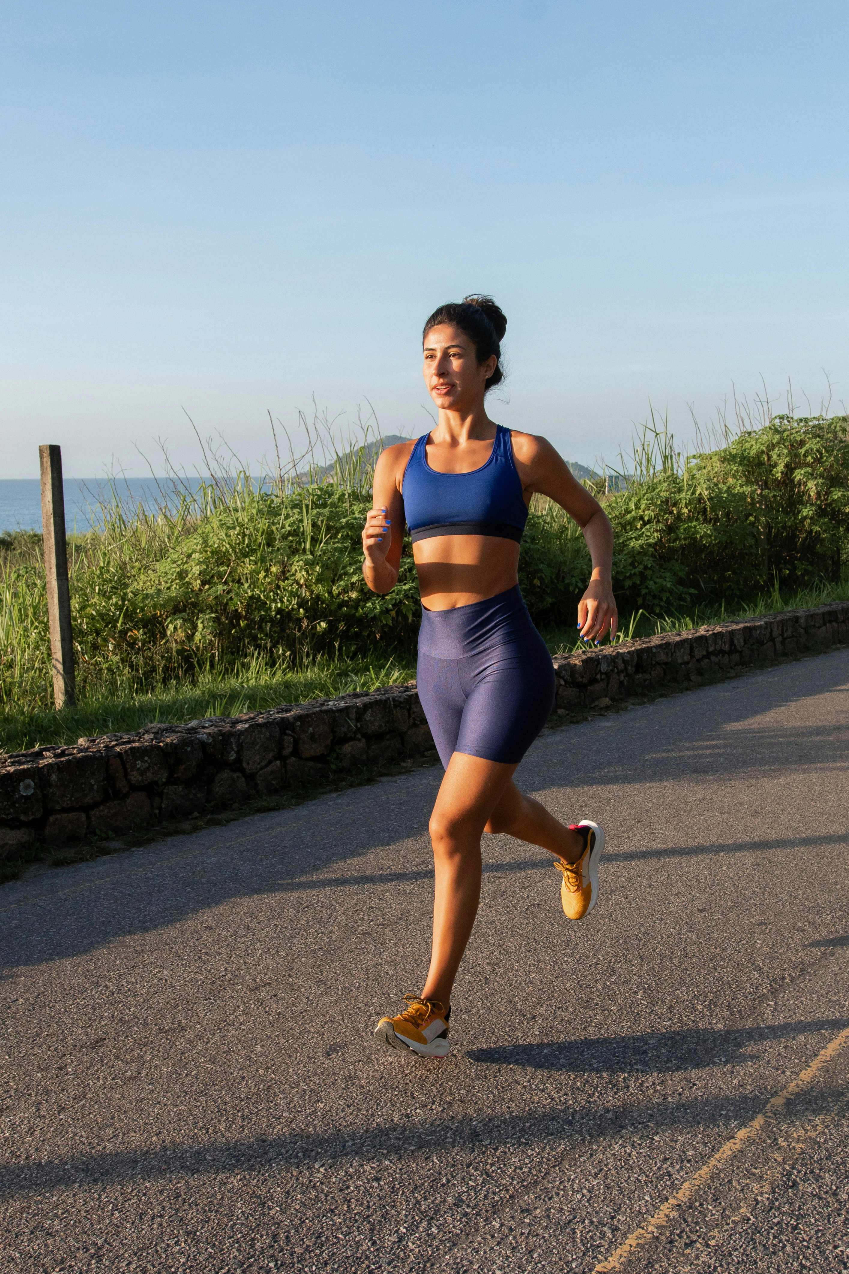 A woman running down a road on a sunny day